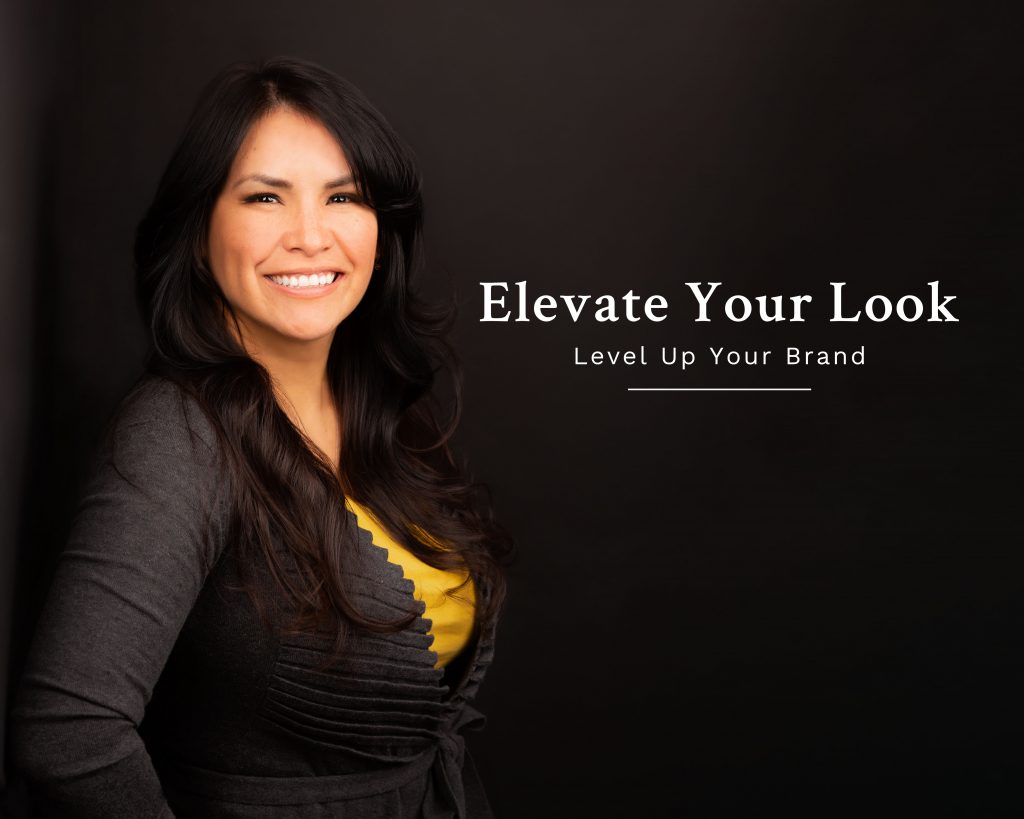 Studio headshot of woman standing against black wall. Text on image reads elevate your look level up your brand.